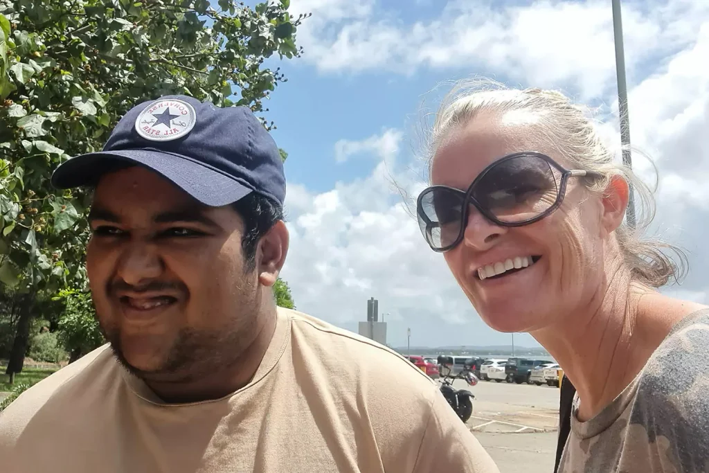 A young man with a disability is smiling while with his support provider