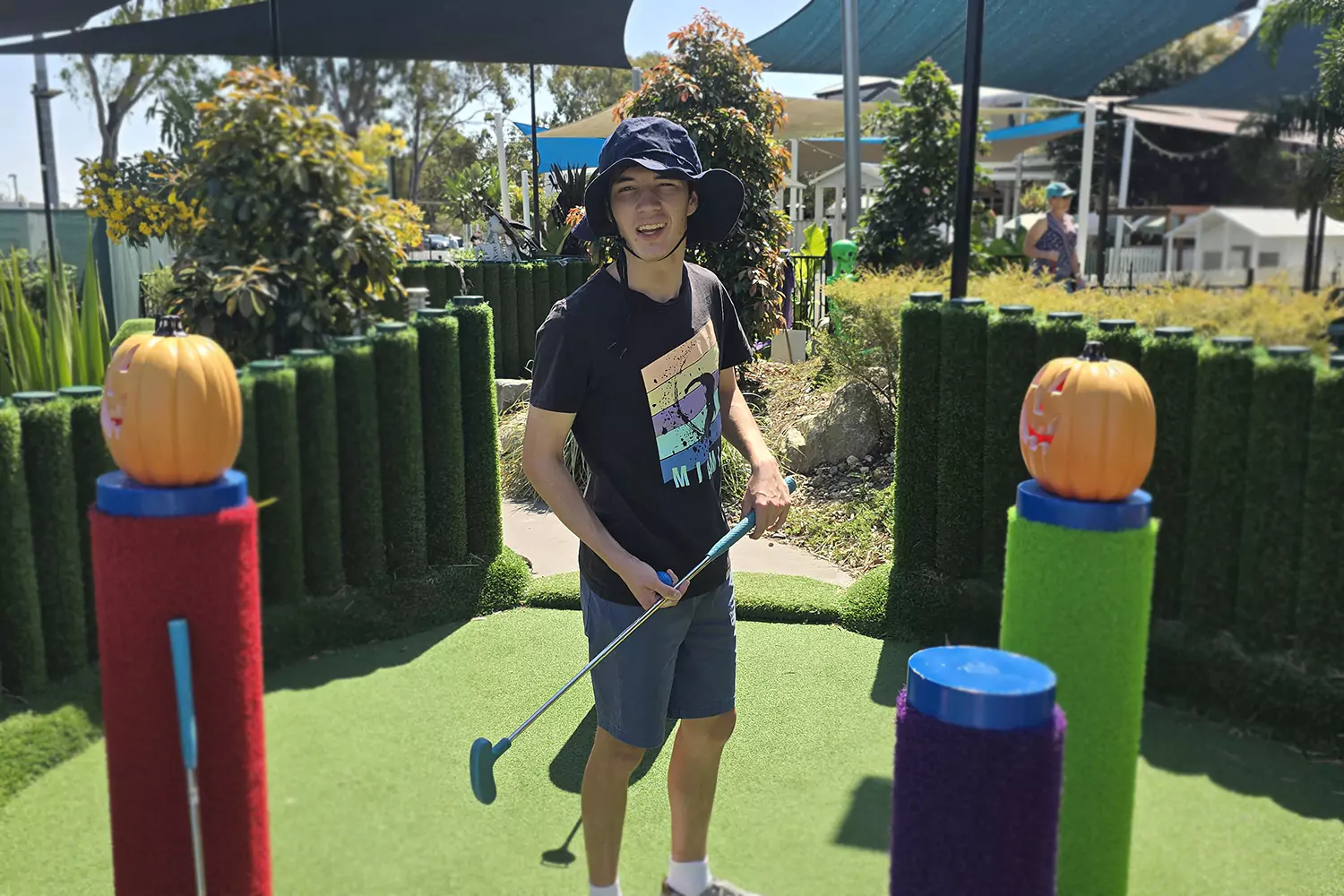 A young man with a disability is playing putt putt golf