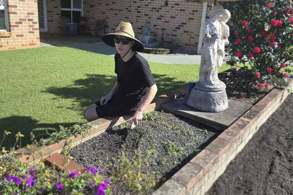 A young man with a disability is gardening outdoors