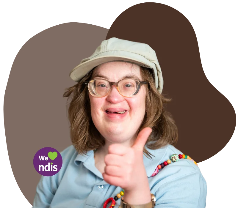 A woman with down syndrome is smiling and giving thumbs up