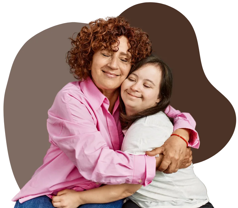 A young woman with down syndrome is hugging her support provider